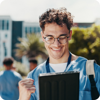 A man with a stethoscope around his neck and looking at a tablet.
