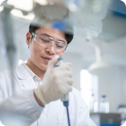 A man wearing safety googles and using a syringe.